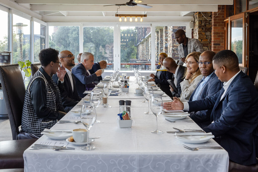 A diverse group of senior leaders exchanging perspectives around a Hela table